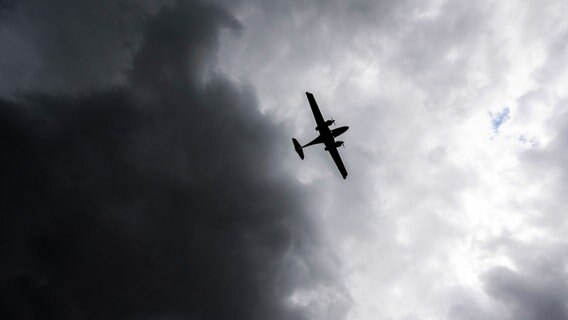 Ein Flugzeug landet vor dunklen Wolken während stärkerer Sturmböen am Flughafen Hannover. © dpa-Bildfunk Foto: Julian Stratenschulte