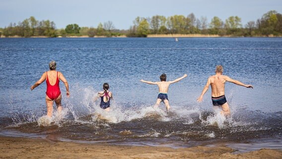 Isernhagen: Eine Familie läuft bei sonnigem Wetter in den Hufeisensee in der Region Hannover. © dpa-Bildfunk Foto: Moritz Frankenberg