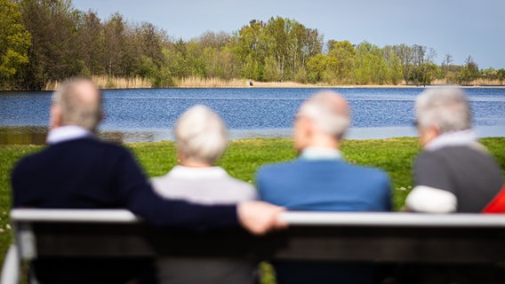 Menschen verweilen bei sonnigem Wetter am Ufer vom Hufeisensee in der Region Hannover auf einer Parkbank. © dpa-Bildfunk Foto: Moritz Frankenberg