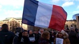 Eine Frau bei einer Kundgebung schwenkt eine französische Flagge. Eine Frau bei einer Kundgebung schwenkt eine französische Flagge. © TeleNewsNetwork