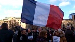 Eine Frau bei einer Kundgebung schwenkt eine französische Flagge. © TeleNewsNetwork 