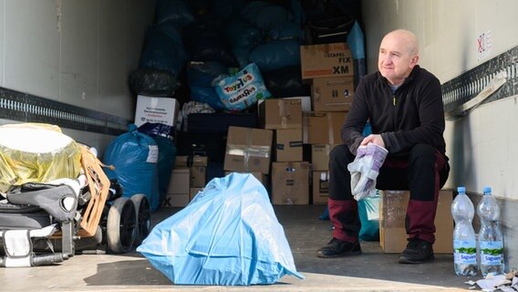 Ein Helfer sitzt vor der ukrainisch-katholischen Kirche St. Wolodymyr in einem LKW mit Hilfsgütern für die Ukraine. © dpa Foto: Julian Stratenschulte