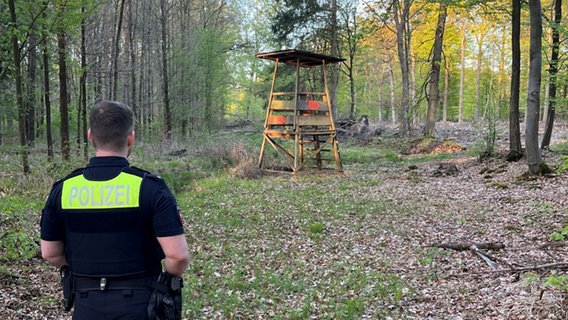 EIn Polizist steht vor einem Hochstand, in dem ein gefesselter Mann gefunden wurde. © Polizeikommissariat Bückeburg 