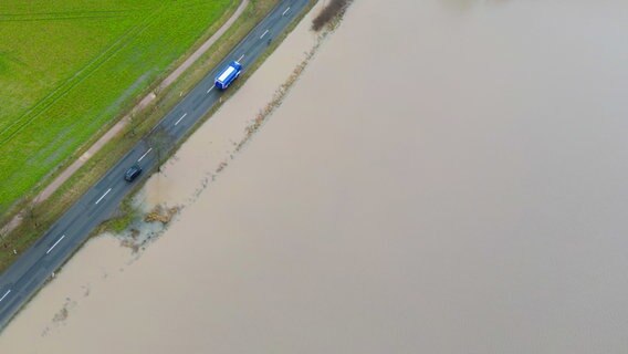 Autos fahren neben einem überfluteten Feld über eine Landstraße zwischen Sarstedt und Ruthe im Landkreis Hildesheim. © dpa Foto: Julian Stratenschulte