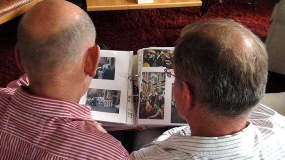 Heinz-Friedrich Harre (l.) und Reinhard Lüschow schauen sich auf dem Sofa sitzend ein Fotoalbum an. © NDR Foto: Kathrin Riggert