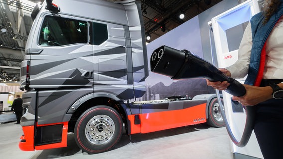 Eine Mitarbeiter von MAN hält auf der Internationalen Automobil-Ausstellung IAA Transportation für Nutzfahrzeuge in der Messe Hannover auf dem Stand von MAN einen Stecker des Megawatt-Ladesystem MCS vor einem neuen Elektro-LKW MAN E-Truck. © Julian Stratenschulte/dpa Foto: Julian Stratenschulte