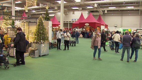 Menschen laufen bei der Infa durch eine Messehalle in Hannover. © NDR 