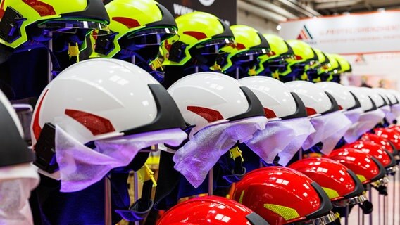 Helme für Rettungskräfte stehen aufgereiht auf einer Messe. © Michael Matthey/dpa Foto: Michael Matthey