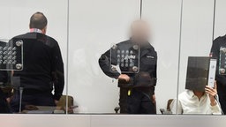 Die beiden Angeklagten Ebrahim H. B. (26, l.) und Ayoub B. (27, r, verdeckt von einem Aktenordner) sitzen zu Beginn der Verhandlung in einem mit Sicherheitsglas abgetrennten Raum im Gerichtssaal des Oberlandesgerichts in Celle. © dpa Bildfunk Foto: Holger Hollemann