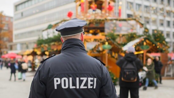 Ein Polizist steht an der Weihnachtspyramide am Kröpcke. © Julian Stratenschulte/dpa Foto: Julian Stratenschulte