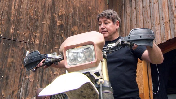 Chris Distin, Sammler von Requisiten aus James-Bond-Filmen, mit einem Motorrad © NDR 