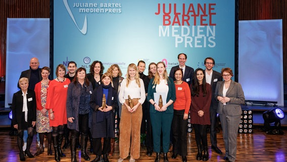 Eine Gruppe Menschen posiert, nach der Preisverleihung des Juliane Bartels Medienpreis, auf einer Bühne. © Ole Spata Foto: Ole Spata
