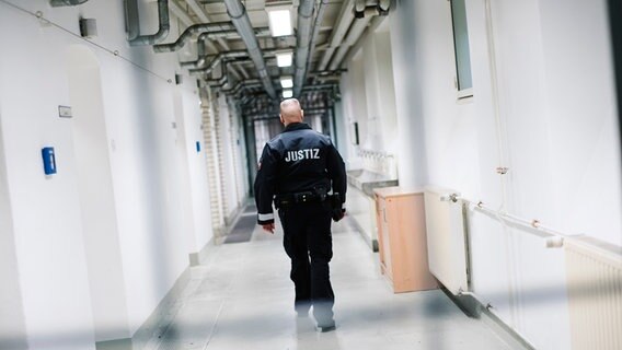 Ein Beamter des Justiz Vollzuges geht durch einen Gang in einem Gefängnistrakt. © NDR Foto: Julius Matuschik