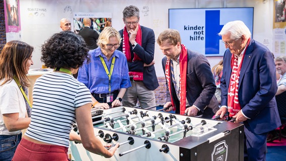 Bundespräsident Frank-Walter Steinmeier (r) spielt bei seinem Besuch des Evangelischen Kirchentags am Stand der Kindernothilfe Tischfußball. © dpa-Bildfunk Foto: Moritz Frankenberg