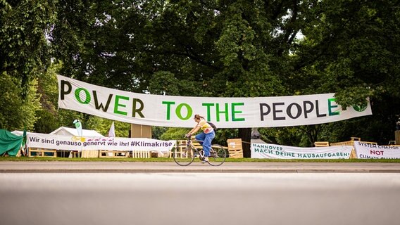 Vor einem Umwelt-Protest-Camp hängt ein Banner mit der Aufschrift: "Power to the people". © dpa-Bildfunk Foto: Moritz Frankenberg