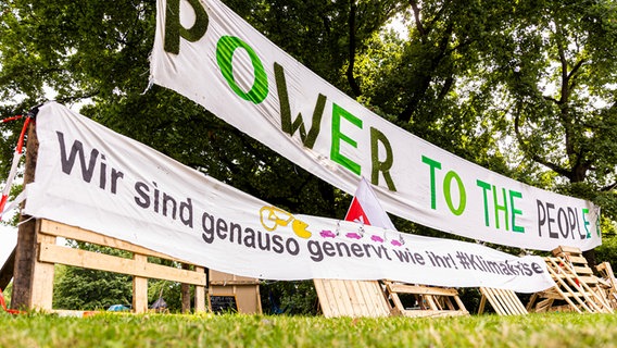 Vor einem Umwelt-Protest-Camp hängt ein Banner mit der Aufschrift: "Power to the people". © picture alliance Foto: Moritz Frankenberg