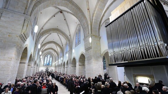 Blick in den Innenraum der Stiftskirche Loccum. Im Vordergrund ist eine große Orgel zu sehen, dahinter sitzen in den Bankreihen viele Menschen. © dpa Foto: Peter Steffen