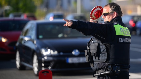 Ein Polizist winkt Autofahrer zu einer Kontrolle raus. © picture alliance/dpa | Julian Stratenschulte Foto: Julian Stratenschulte