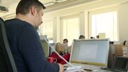 Ein Mann sitzt in einem Büro des Corona-Krisenstabs in Hannover, telefoniert und hat vor sich auf dem Laptop ein Kurvendiagramm geöffnet. © NDR 