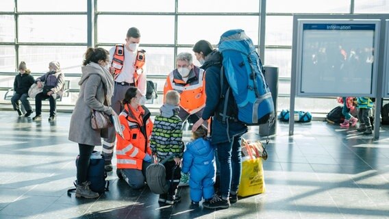 Eine Frau sucht mit Kindern ärztlichen Rat bei Helfern des Roten Kreuzes. © dpa Foto: Ole Spata