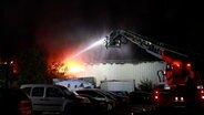 Einsatzkräfter der Feuerwehr löschen eine brennende Lagerhalle. © TeleNewsNetwork 