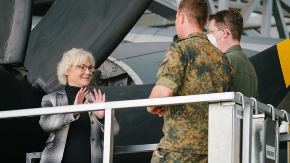 Bundesverteidigungsministerin Christine Lambrecht (SPD) spricht bei ihrem Besuch beim Lufttransportgeschwader 62 im niedersächsischen Wunstorf vor dem Propeller eines A400M mit Soldaten. © dpa-Bildfunk Foto: Ole Spata