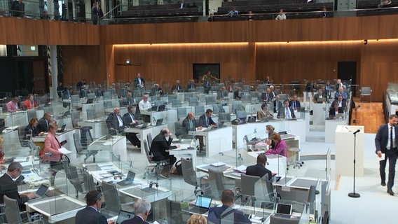 Personen sitzen im Landtag in Niedersachsen. Die Tische sind mit transparenten Scheiben ausgestattet. © Landtag NDS 