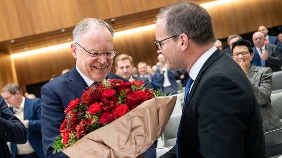 Stephan Weil (SPD, r), Ministerpräsident von Niedersachsen, freut sich nach seiner Wiederwahl während der konstituierenden Sitzung im niedersächsischen Landtag über den Blumenstrauß. © Sina Schuldt/dpa Foto: Sina Schuldt/dpa