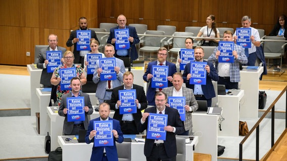 Fraktionsmitglieder der Alternative für Deutschland (AfD) halten Schilder mit Aufschrift "Keine Heizung ist illegal" während der Debatte im niedersächsischen Landtag. © dpa Foto: Julian Stratenschulte