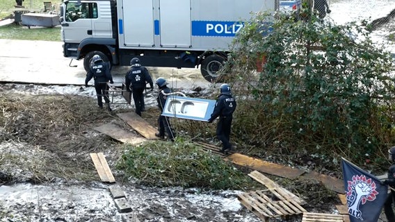 Einsatzkräfte der Polizei tragen Mobiliar aus dem Protestcamp in der Leinemasch. © NEWS5 