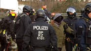 Eine vermummte Person wird bei einer Räumungsaktion der Polizei in der Leinemasch in Hannover abgeführt. © NDR 