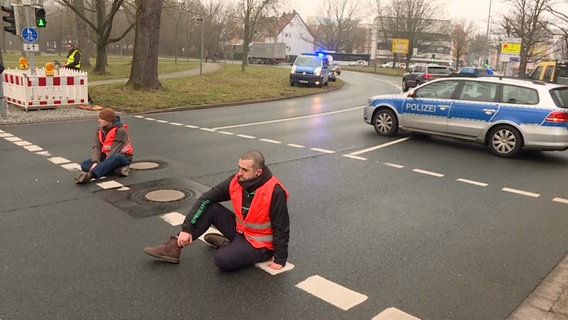 Aktivisten der Klimabewegung Letzte Generation kleben mit ihren Händen am Deisterkreisel in Hannover. © TeleNewsNetwork 