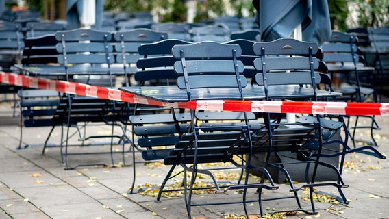 Tische und Stühle stehen abgesperrt vor einem geschlossenen Restaurant in der Innenstadt. © picture alliance Foto: Hauke-Christian Dittrich