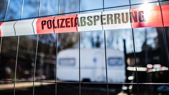 Auf dem Campingplatz Eichwald, in der inzwischen eingezäunten Parzelle des mutmaßlichen Täters, hängt vor dem versiegelten Campingwagen eine Banderole mit der Aufschrift: "Polizeiabsperrung". © picture alliance/dpa Foto: Guido Kirchner