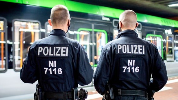 Zwei Polizisten stehen vor einer Straßenbahn in Hannover. © picture alliance/Hauke-Christian Dittrich Foto: Hauke-Christian Dittrich