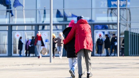 Eine Frau und ein Kind laufen vor der Messehalle 27 auf der Messe Hannover. © picture alliance/dpa Foto: Julian Stratenschulte