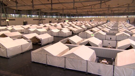 Zelte sind in einer Messehalle aufgebaut. © NDR 
