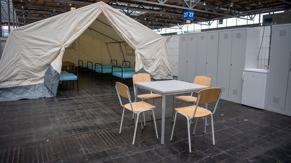 2022: Eine Notunterkunft für Geflüchtete (Zelt mit Betten, davor ein Tisch mit Stühlen) in einer Messehalle (Laatzen, Region Hannover). © picture alliance/dpa | Lino Mirgeler Foto: Lino Mirgeler