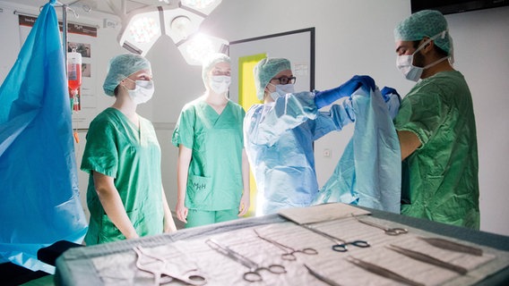 Medizinstudenten üben im "Skills Lab" der Medizinischen Hochschule Hannover (MHH) in einem nachgebildeten OP-Raum das hygienisch korrekte Anlegen eines OP-Kittels (gestellte Szene). Medizinstudenten üben im "Skills Lab" der Medizinischen Hochschule Hannover (MHH) in einem nachgebildeten OP-Raum das hygienisch korrekte Anlegen eines OP-Kittels (gestellte Szene). © picture alliance/dpa/Julian Stratenschulte Foto: Julian Stratenschulte