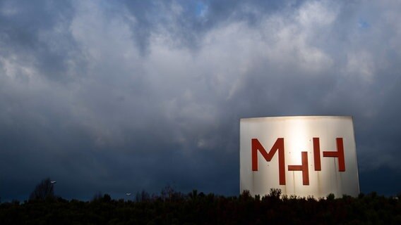 Vor dunklem, wolkenverhangenem Himmel ist ein großer Aufsteller mit dem Logo der Medizinischen Hochschule Hannover zu sehen. © dpa / picture-alliance Foto: Julian Stratenschule