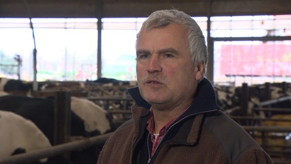 Ein Landwirt gibt ein Interview in einem Kuhstall. © NDR 