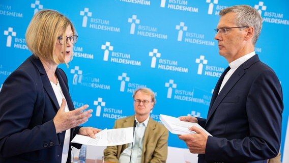 Antje Niewisch-Lennartz, Vorsitzende Richterin am Verwaltungsgericht a. D. und ehemalige Justizministerin in Niedersachsen, übergibt Heiner Wilmer, Bischof von Hildesheim, einen Abschlussbericht zu sexualisierter Gewalt und Machtmissbrauch im Bistum Hildesheim auf einer Pressekonferenz. © dpa-Bildfunk Foto: Moritz Frankenberg