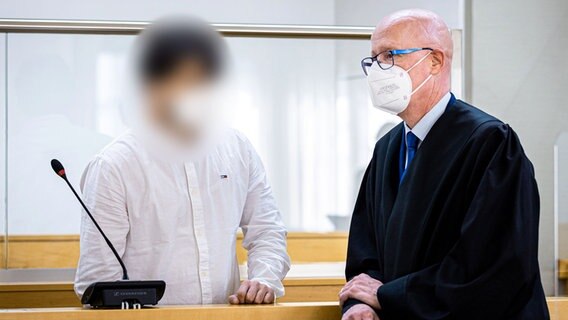 Einer der beiden Angeklagten steht bei Prozessauftakt in einem Saal vom Landgericht Hannover und spricht mit seinem Verteidiger Matthias Fiedler. © dpa-Bildfunk Foto: Moritz Frankenberg/dpa