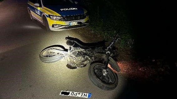 Ein beschädigtes Motorrad liegt nach einer Kollision mit einem Streifenwagen auf einer Straße bei Husum. © Polizei Nienburg 