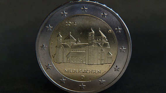Eine neue Zwei-Euro-Münze mit dem Motiv der Michaeliskirche aus Hildesheim steht in Hannover vor einem dunklen Hintergrund. © dpa-Bildfunk Foto: Jochen Lübke