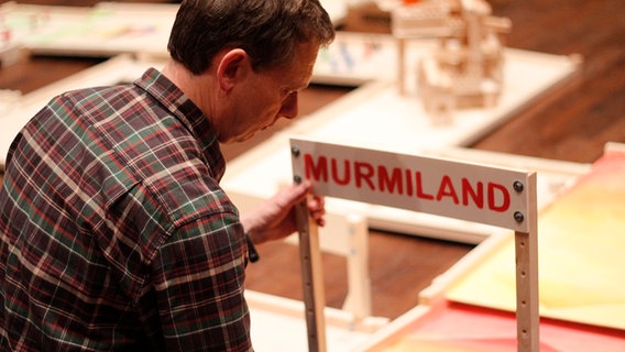 Ortwin Grüttner bastelt an einem Schild mit der Aufschrift "Murmland" im Ricklinger Freizeitheim. © NDR Foto: Henning Martin