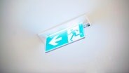 Ein Schild mit einem Pfeil und einer laufenden Person an der Decke. © NDR Foto: Julius Matuschik