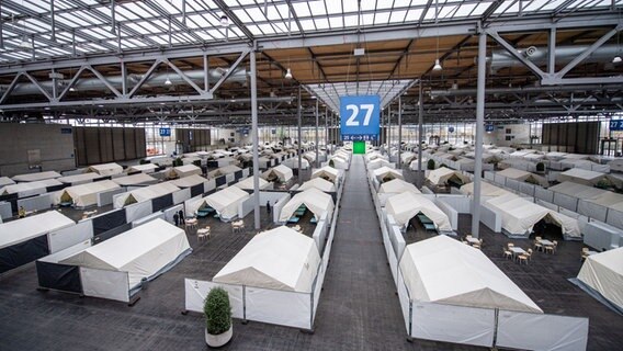 Voneinander abgetrennte Zeltdörfer für die Geflüchteten stehen in der Halle 27 der Messe. © dpa Foto: Lino Mirgeler