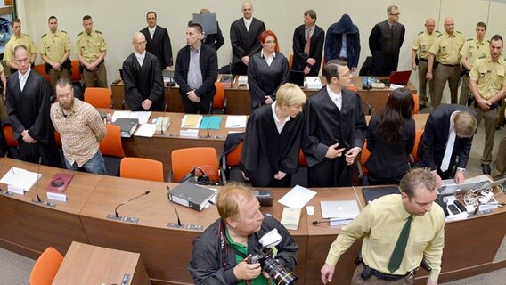 Die Angeklagten und ihre Anwälte erheben sich zu Beginn des NSU-Prozesses in München. Unter ihnen auch Holger G. aus Lauenau (hintere Reihe mit Aktenmappe vor dem Gesicht). © dpa-Bildfunk Foto: Peter Kneffel