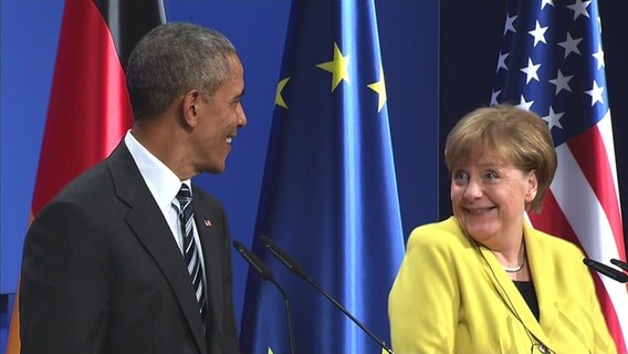 Angela Merkel blickt während einer Pressekonferenz im Schloss Herrenhausen lächelnd und mit weit aufgerissenen Augen in Richtung Barack Obama. © NDR 